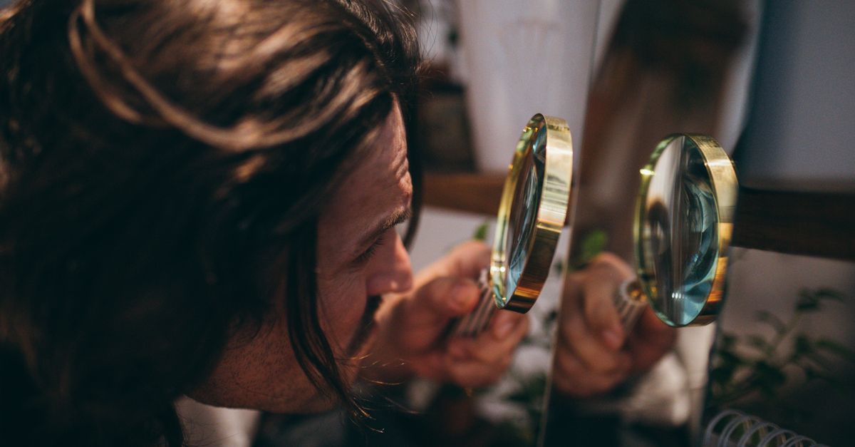 Man inspecting his hair with a magnifying glass, the manual version of a trichoscan