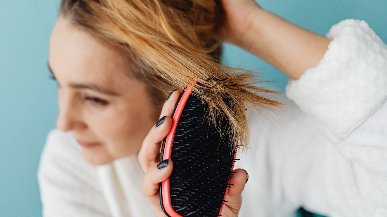 Woman brushing her hair and noticing the change, asking what causes thinning hair