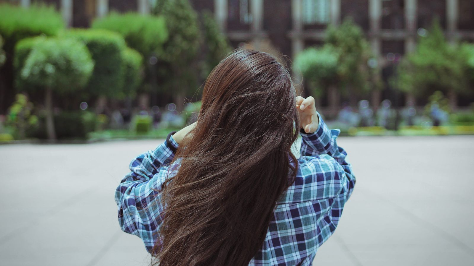 Woman adjusting long hair, a common picture of why hair falls flat by the afternoon