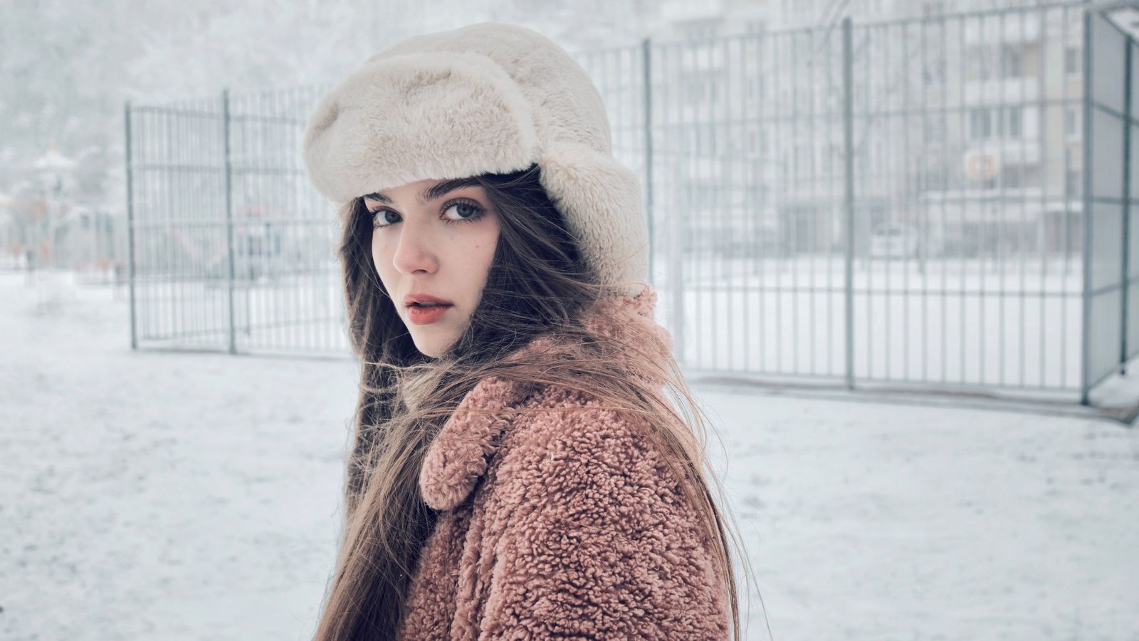 Woman outdoors in a snowy street in winter clothing, the conditions that make winter hair care harder
