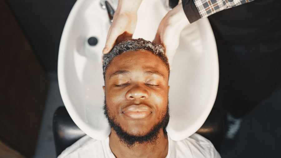 Man having his hair washed, choosing a shampoo for hair loss that cleans gently